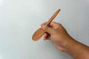 Hand holding wooden spoon and fork isolated on white background photo