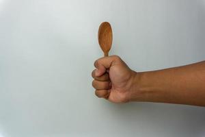 Hand holding wooden spoon and fork isolated on white background photo