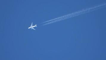 Düsenflugzeug, das hoch in den Himmel fliegt, hinterlässt Kondensstreifen am klaren blauen Himmel. video