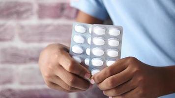 Adult holds two foil pill packs full of oval white pills video