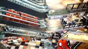 Looking down at levels in a mall with shoppers going up and down the escalators video