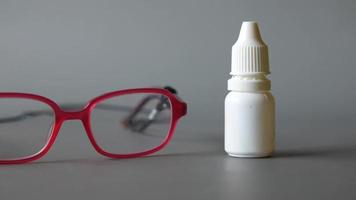 óculos de armação vermelha e um frasco de colírio video