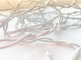 Twisted white wires of a garland in white rubber insulation with light bulbs on a white background photo