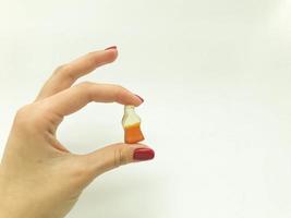 dulces de mermelada. una chica con manicura roja sostiene dulces en forma de botella con limonada. dulce, caramelo de azúcar en forma de botella de cola foto