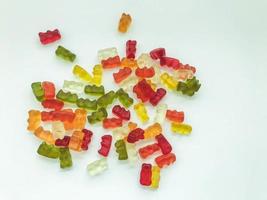 gummy bears of different colors lie on a matte white background. delicious variety of sweets. gelatinous gummies desired. delicious bears, edible sweet dessert photo
