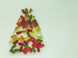 árbol de navidad hecho de deliciosas y dulces gomitas. mermelada en forma de osos, botellas de limonada. árbol de navidad hecho de caramelos brillantes, coloridos y dulces foto