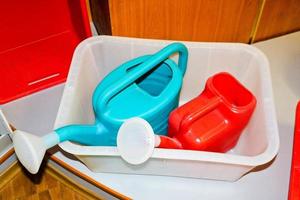 Multi-colored plastic red blue watering cans with a handle for watering plants, flowers photo