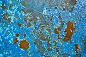 The texture of the iron metal painted blue paint old battered scratched cracked ancient rusty metal sheet wall with corrosion. The background photo