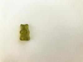 green gelatinous bear on a matte orange background. gummy figurine in the shape of an animal. baby candy. teddy bear, gammi. appetizing figurine for eating photo