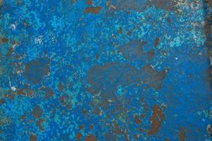 The texture of the iron metal painted blue paint old battered scratched cracked ancient rusty metal sheet wall with corrosion. The background photo