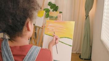 African American girl concentrates on acrylic color picture painting on canvas with a paintbrush in an art classroom, creative learning with talents and skills in elementary school studio education. video