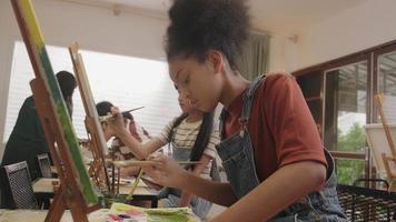une fille noire se concentre sur la peinture acrylique couleur sur toile avec des enfants multiraciaux dans une classe d'art, l'apprentissage créatif avec des talents et des compétences dans l'enseignement en studio de l'école primaire. video