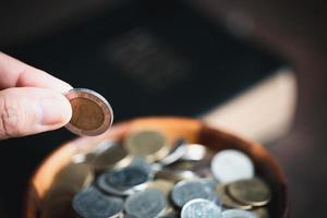 una décima o diezmo es la base sobre la cual la biblia nos enseña a dar una décima parte de las primicias a dios. monedas con la santa biblia. concepto bíblico de ofrenda cristiana, generosidad y entrega de diezmos en la iglesia. foto