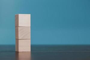 Stacking blank wooden cubes on blue background with copy space for input wording and infographic icon. Empty brown wooden object block for symbol icon put technology, zero gravity, business concept. photo