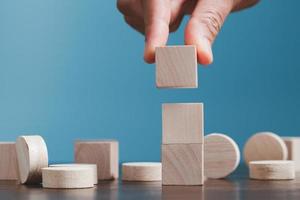 Stacking blank wooden cubes on blue background with copy space for input wording and infographic icon. Empty brown wooden object block for symbol icon put technology, zero gravity, business concept. photo