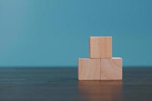 Stacking blank wooden cubes on blue background with copy space for input wording and infographic icon. Empty brown wooden object block for symbol icon put technology, zero gravity, business concept. photo