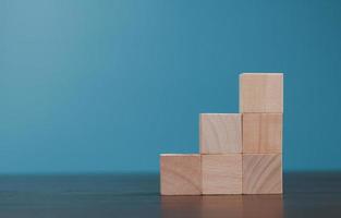 Stacking blank wooden cubes on blue background with copy space for input wording and infographic icon. Empty brown wooden object block for symbol icon put technology, zero gravity, business concept. photo