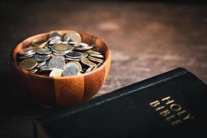 One tenth or tithe is basis on which Bible teaches us to give one tenth of first fruit to God. coins with Holy Bible. Biblical concept of Christian offering, generosity, and giving tithes in church. photo