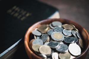 One tenth or tithe is basis on which Bible teaches us to give one tenth of first fruit to God. coins with Holy Bible. Biblical concept of Christian offering, generosity, and giving tithes in church. photo