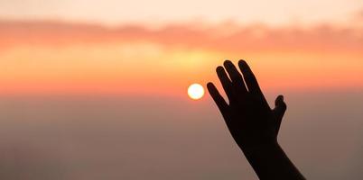 Silhouette of woman hand praying spirituality and religion, female worship to god. Christianity religion concept. Religious people are humble to God. Christians have hope faith and faith in god. photo