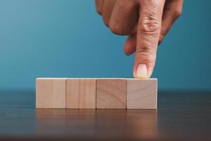 Stacking blank wooden cubes on blue background with copy space for input wording and infographic icon. Empty brown wooden object block for symbol icon put technology, zero gravity, business concept. photo