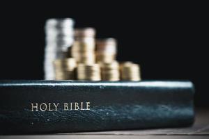 One tenth or tithe is basis on which Bible teaches us to give one tenth of first fruit to God. coins with Holy Bible. Biblical concept of Christian offering, generosity, and giving tithes in church. photo