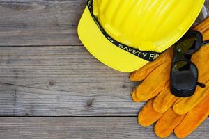 equipo de seguridad seguridad de construcción estándar ropa de trabajo de protección industrial herramienta con sombrero amarillo casco de seguridad gafas y guantes sobre fondo de madera