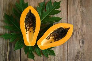 papaya fruits on wooden backgroud, fresh ripe papaya tropical fruit with papaya seed and leaf leaves from papaya tree - top view photo