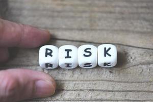 Risk concept with block risk with hand on wooden table background photo