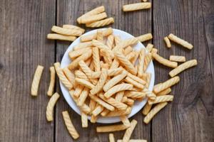prawn crackers stick on white plate and wooden table background , homemade crunchy prawn crackers or shrimp crisp traditional snack photo