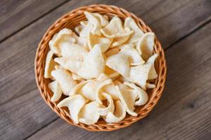 prawn crackers chips on basket and wooden table background - homemade crunchy prawn crackers or shrimp crisp rice for traditional snack photo