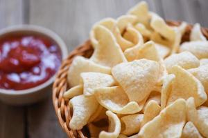 crunchy prawn crackers or shrimp crisp rice and ketchup for traditional snack - prawn crackers chips on basket and wooden table background photo