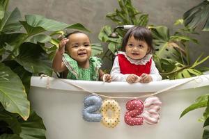 dos bebés de diversidad sentados juntos con el signo de feliz año nuevo 2023 para la celebración de la temporada para la felicidad y el concepto de niño foto