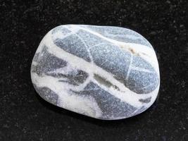 tumbled gray Gneiss stone on dark background photo