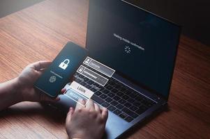 mujer que usa un teléfono inteligente para iniciar sesión esperando la autenticación del escáner en la computadora portátil. concepto de ciberseguridad. protección de datos y acceso seguro a internet. foto