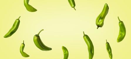 Creative banner with green peppers flying on light yellow background. Long food banner with copy space. photo