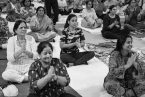 delhi, india, 19 de junio 2022: sesión de ejercicios de yoga en grupo para personas de diferentes grupos de edad en el templo balaji, vivek vihar, día internacional del yoga, gran grupo de adultos que asisten a clases de yoga en blanco y negro foto