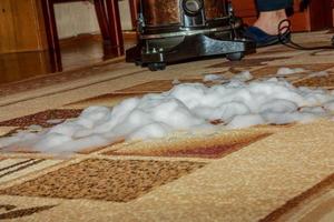 el proceso de limpieza de la alfombra con una aspiradora con filtro de agua. la espuma de limpieza impregna la superficie sucia de la alfombra foto