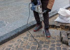 A male worker repairs the pavement with a jackhammer. The work of the municipal service photo