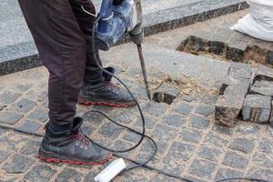 A male worker repairs the pavement with a jackhammer. The work of the municipal service photo