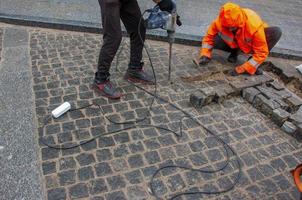 Dnipropetrovsk, Ukraine - 02.10.2022 A male worker repairs the pavement with a jackhammer. The work of the municipal service. photo