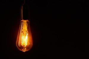 Vintage light bulb on black background, copy space. Glowing edison bulb photo