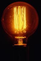 Vintage light bulb on black background, closeup. Glowing edison bulb photo