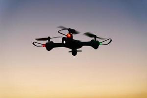 Toy drone quad copter against sunset sky photo