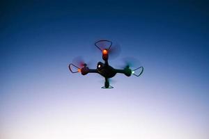 helicóptero quad drone de juguete contra el cielo del atardecer foto