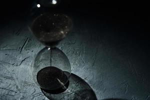 Hourglass on dark background, closeup. Urgency and running out of time concept photo