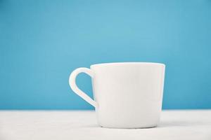 White cup on a blue background with copy space photo