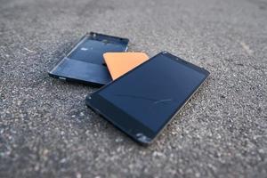 Damaged smartphone with broken touch screen on asphalt photo