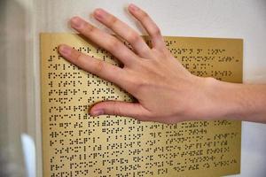 Woman reading braille text on braille plate photo