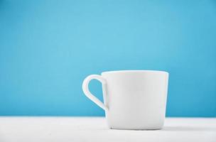 White cup on a blue background with copy space photo